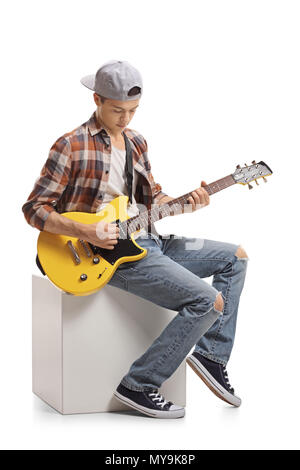 Teenager sitzen auf einem Cube und spielen eine E-Gitarre auf weißem Hintergrund Stockfoto