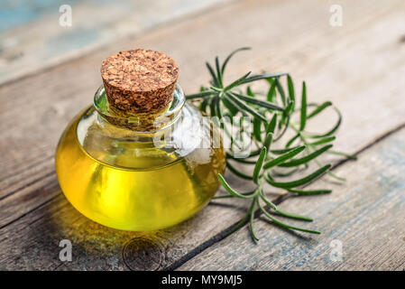 Rosemary wesentliches Öl in einer Glasflasche mit Korken Stopfen und frischem Rosmarin Kraut auf hölzernen Hintergrund Stockfoto
