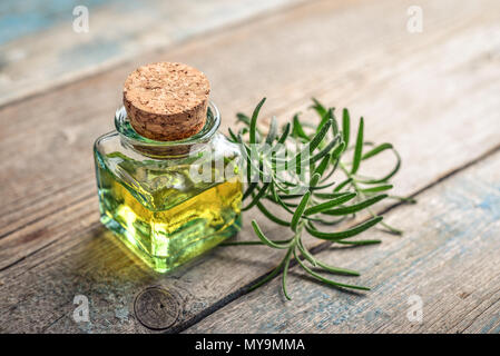 Rosemary wesentliches Öl in einer Glasflasche mit Korken Stopfen und frischem Rosmarin Kraut auf hölzernen Hintergrund Stockfoto