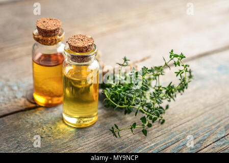 Thymian ätherisches Öl in einer Glasflasche mit Korken Stopfen und frischem Thymian Kraut auf hölzernen Hintergrund Stockfoto