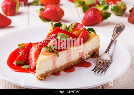 Leckere hausgemachte Cheesecake mit Erdbeeren auf weißem Holztisch. Stockfoto