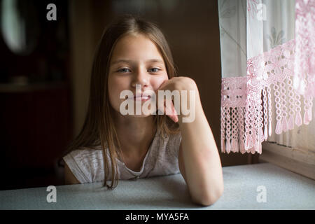 Portrait von Süße 10-jährige Mädchen am Tisch sitzen. Stockfoto