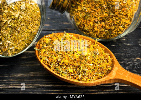 Calendula Blüten getrocknet in Gläser aus Glas und einem hölzernen Löffel auf dem Tisch Stockfoto