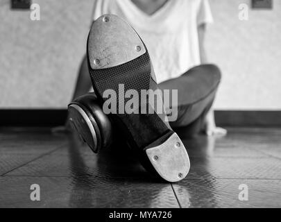 Schwarze und weiße Version von gekreuzten Beinen tippen Sie auf Tänzer und ihre Schuhe Stockfoto