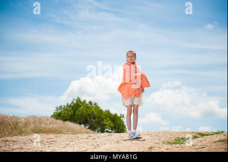 Schöne Mädchen in orange Handtuch eingewickelt stehen draußen auf Wind Stockfoto