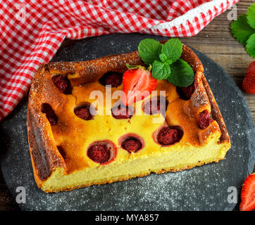 Stück Käsekuchen mit Erdbeeren auf schwarzem Graphit Platte, Ansicht von oben Stockfoto