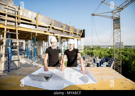 Arbeitnehmer mit Zeichnungen auf der Baustelle Stockfoto
