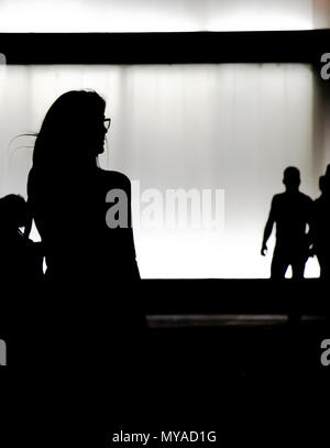 Silhouette einer jungen Frau, die alleine zu Fuß in der Nacht und eine Gruppe von Personen sich nähern Stockfoto