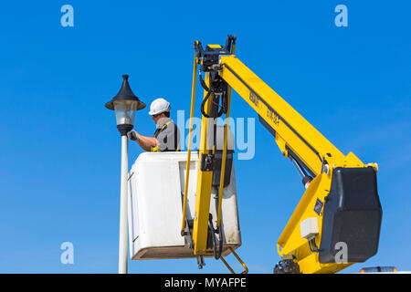 Ein Mann überprüft und tauscht im Juni die Glühbirne in der Straßenlaterne entlang der Promenade in Bournemouth, Dorset, UK Stockfoto