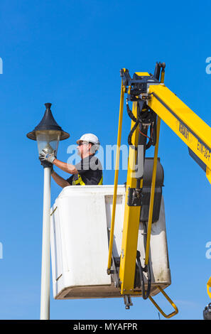 Ein Mann überprüft und tauscht im Juni die Glühbirne in der Straßenlaterne entlang der Promenade in Bournemouth, Dorset, UK Stockfoto