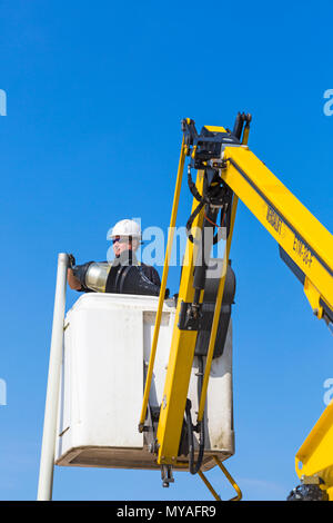 Ein Mann überprüft und tauscht im Juni die Glühbirne in der Straßenlaterne entlang der Promenade in Bournemouth, Dorset, UK Stockfoto