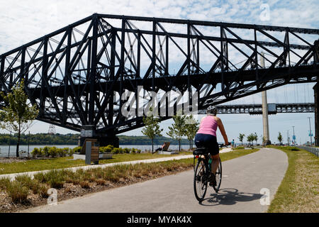 Radfahrer auf der Promenade Samuel de Champlain Radweg in Quebec, mit der St. Lawrence River in Pont du Quebec Brücke jenseits Stockfoto