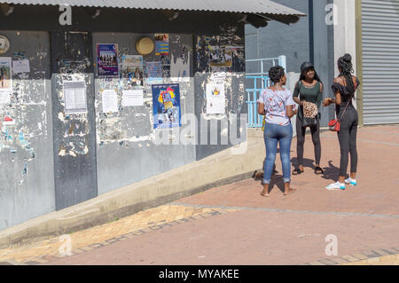 WINDHOEK Namibia - 10. MAI 2018; Gruppe drei afrikanischen Moderne, junge Frauen, die Straße unterhalten Vor grungy Wand der peeling Poster. Stockfoto
