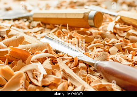 Meißel in Holzspäne auf den Schreibtisch gelegt. Carving Tools in der Späne liegen. In einem Carving Workshop. Schneiden von lindenholz. Stockfoto