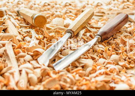 Meißel in Holzspäne auf den Schreibtisch gelegt. Carving Tools in der Späne liegen. In einem Carving Workshop. Schneiden von lindenholz. Stockfoto