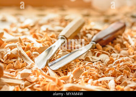 Meißel in Holzspäne auf den Schreibtisch gelegt. Carving Tools in der Späne liegen. In einem Carving Workshop. Schneiden von lindenholz. Stockfoto