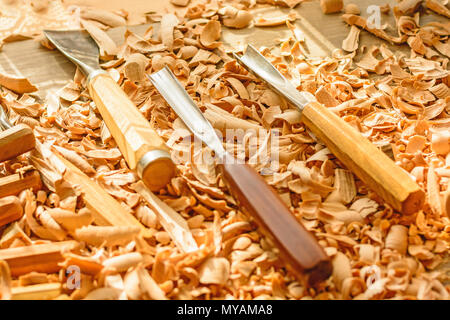 Meißel in Holzspäne auf den Schreibtisch gelegt. Carving Tools in der Späne liegen. In einem Carving Workshop. Schneiden von lindenholz. Stockfoto