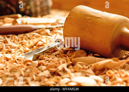 Meißel in Holzspäne auf den Schreibtisch gelegt. Carving Tools in der Späne liegen. In einem Carving Workshop. Schneiden von lindenholz. Holz- Hammer auf einer wor Stockfoto