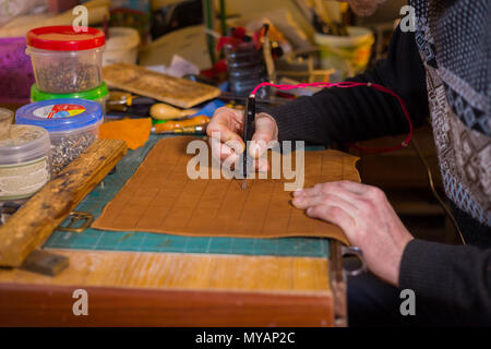 Professionelle männlichen Skinner, Tanner, dekorative Details auf Leder Ausgangsbedingungen für strategisches Brettspiel - tafl mit speziellen pyrographic Maschine Stockfoto