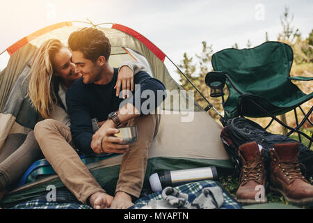 Romantisches Paar Camping im Freien und sitzen in einem Zelt. Glücklich der Mann und die Frau auf einer romantischen Camping Urlaub. Stockfoto