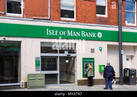 Menschen mit einem Geldautomaten Geldautomaten außerhalb der Insel Man Bank Filiale in Douglas, Isle of Man, Britische Inseln Stockfoto