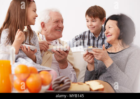 Großeltern und Enkel lächelnd und essen einen Kuchen Stockfoto