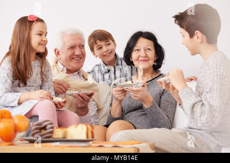 Glückliche Familie sitzt auf einem Sofa und einem Dessert Stockfoto