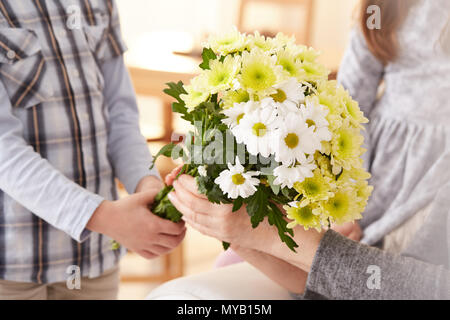 Junge geben einen Blumenstrauß an eine Frau Stockfoto