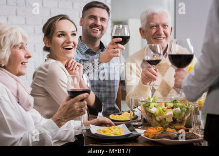 Glückliche Familie beim Abendessen, Toasten, Gläser mit Rotwein Stockfoto