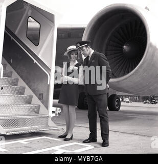 1973, historische, männlichen und weiblichen Besatzung des Gerichtshofes Charter Airlines stehen auf dem Asphalt an der Unterseite des tragbaren Treppe Passagiere an Bord der Lockheed Tristar willkommen zu heißen, (L-1011), die technologisch fortgeschrittenen widebody Verkehrsflugzeug der Welt. Die britische Firma Gericht Linie Luftfahrt waren die erste europäische Fluggesellschaft, die Lockheed Großraumflugzeuge zu betreiben und hatte aircrew Uniformen von der Modedesignerin Mary Quant. Stockfoto