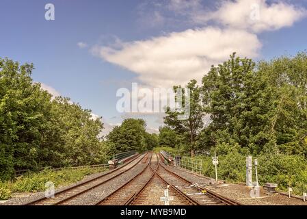 Bahn Linien Überqueren einer Brücke über den Fluss Ouse in York. Bäume und Sträucher sind auf beiden Seiten mit einem blauen, bewölkter Himmel oben. Stockfoto