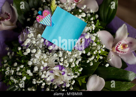 Blank Blue Card mit Orchideen Blumen, minimalistischen Stil. Leeren Karton Karte mit Blumen. Grußkarte mit weißen Blumen Blumenstrauß. Postkarte mit frischen Blumen und leeren tag für Ihren Text. Stockfoto