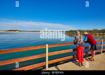 Ein Mann und eine Frau lehnte sich auf einen Zaun an der Kostenposition suchen, Nambucca Heads, New South Wales, Australien Stockfoto