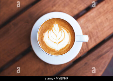 Eine Tasse Kaffee mit Latte Art auf hölzernen Tisch. Ansicht von oben, morgen stimmung, italienischer Cappuccino. Stockfoto