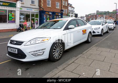 Taxistand mit weißen Taxis in New Quay Straße Whitby, North Yorkshire England Großbritannien warten Stockfoto