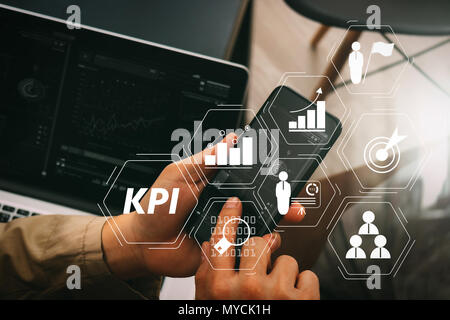 Key Performance Indicator (KPI) workinng mit Business Intelligence (BI) Metriken erreichen und geplante Ziel zu messen. Hand mit Smart Phone und Stockfoto