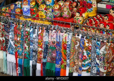 Viele bunte Gewebe Schals und malte Puppen - matryoshkas, sogenannte Russische Souvenirs, liegen auf dem Zähler in einer Street Store und Warten touri Stockfoto