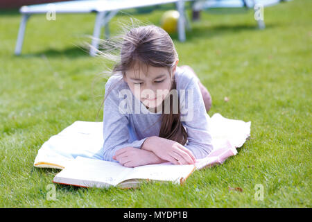 Mädchen liegt auf Gras zu lesen. Stockfoto