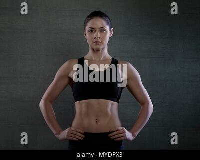 Junge Frau in Sports top mit Händen auf den Hüften, Portrait. Stockfoto