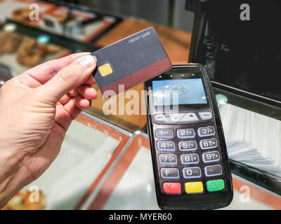 Männliche hand mit einer Kreditkarte eine kontaktlose Zahlung an einem POS-Terminal in einer Bäckerei zu speichern. Stockfoto