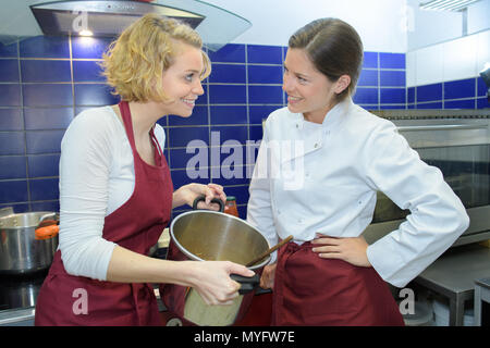 Zwei weibliche Chefs in gastronomische Küche tragen weiße kochen Uniformen Stockfoto