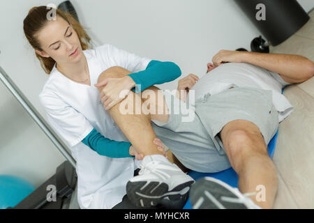 Weibliche physio Therapeuten arbeiten auf männliche Patienten Beine Stockfoto