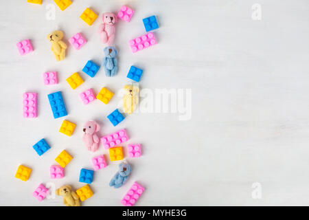 Ansicht von oben über mehrfarbige Spielzeug Ziegel und Plüsch Bären auf weißem Holz- Hintergrund. Stockfoto