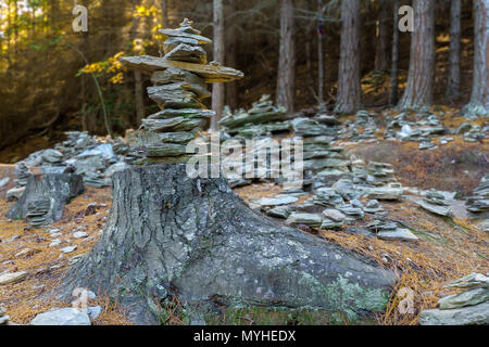 Stein STAPELN IM HOLZ. Stapel der Steine im Gleichgewicht ruhen auf einem alten Baumstumpf im Wald. Stockfoto