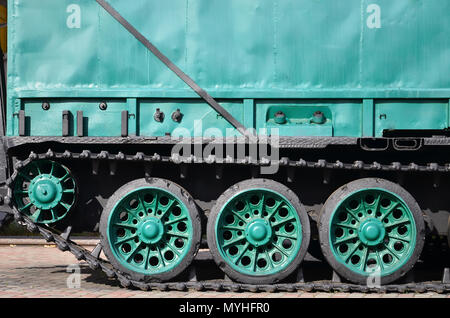 Seitenansicht des Fahrzeugs auf einen Caterpillar Track mit schwarzen Titel und grünen Rädern und einer Seite metall Wand Stockfoto