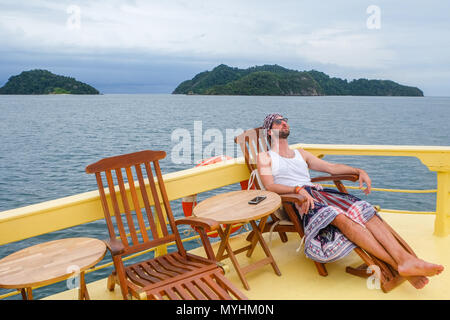 30. April 2018 - Myeik Archipel, Myanmar. Passagier auf Kreuzfahrtschiff Hören von Musik auf dem Smartphone auf der Sonnenterrasse von Kreuzfahrtschiff Stockfoto