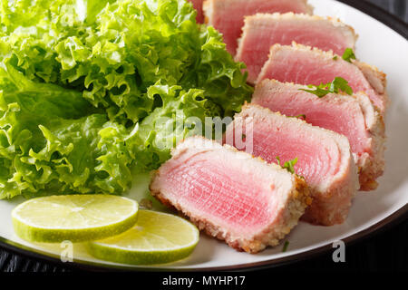 Thunfisch Steak in Paniermehl Panko mit Salat und Kalk closeup auf einem Teller. Horizontale Stockfoto