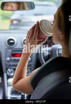 Frau trinkt Kaffee während der Fahrt Stockfoto