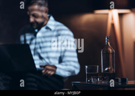 In der Nähe von Glas Flasche mit Alkohol. Workaholic mit Alkohol Problem Stockfoto