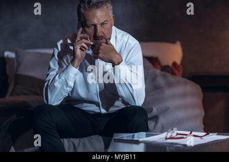 Müde Geschäftsmann am Telefon zu sprechen. Der Mangel an Zeit für das Familienleben Stockfoto